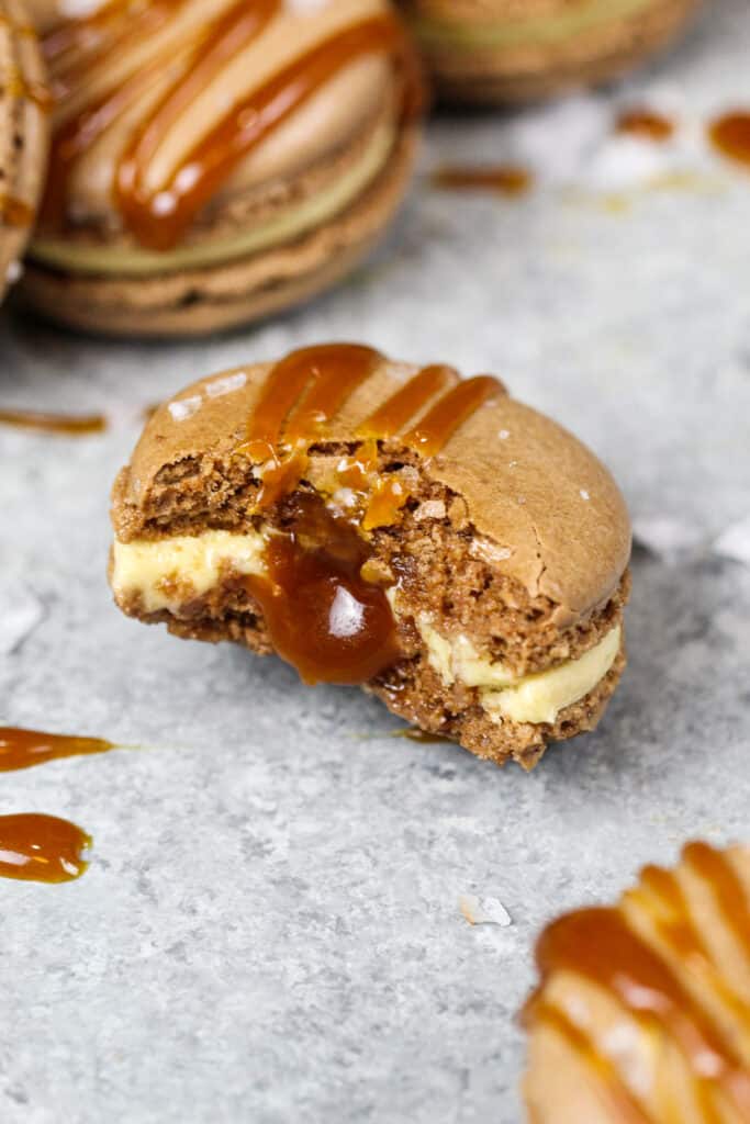 image of a salted caramel macaron that's been bitten into to show how full the macaron shell is