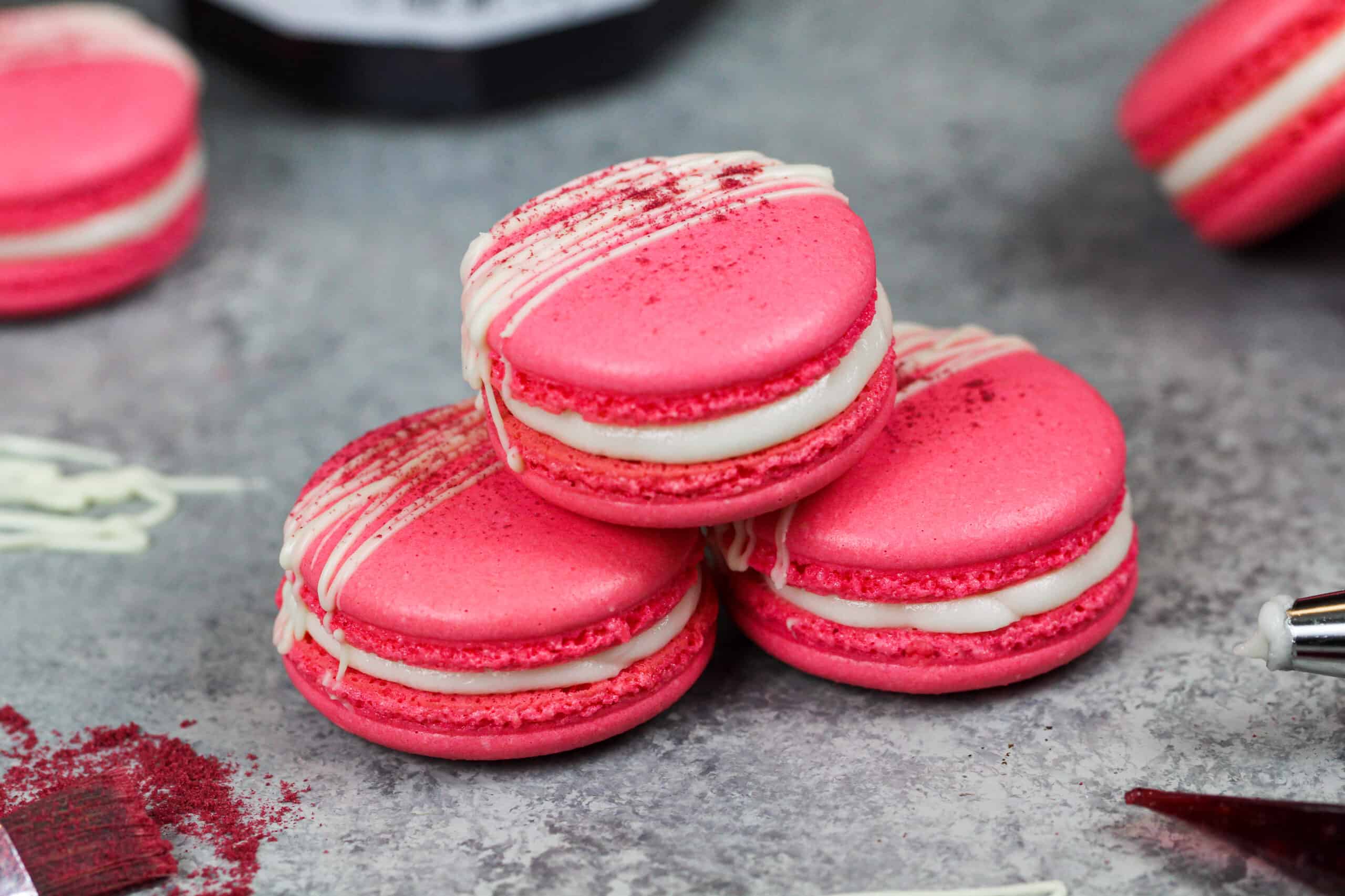 image of french raspberry macarons that have been filled with raspberry jam and buttercream and drizzled with white chocolate as a decoration