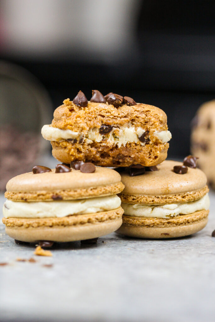 image of cookie dough macarons filled with cookie dough buttercream that have been bitten into to show their full shell