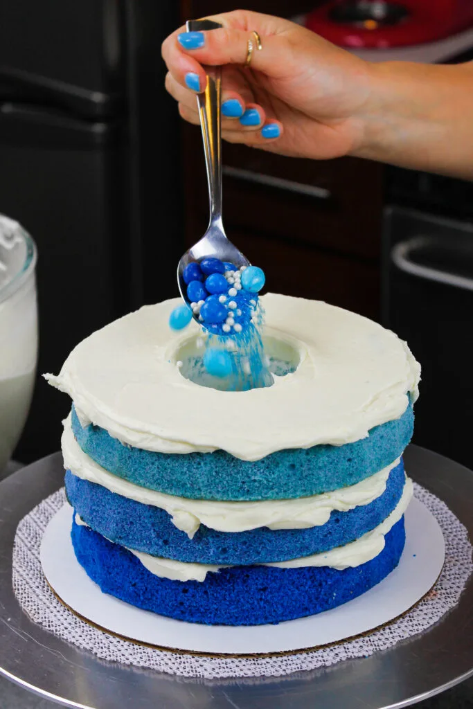 image of a blue ombre cake being filled with blue candy and sprinkles for a boy gender reveal cake