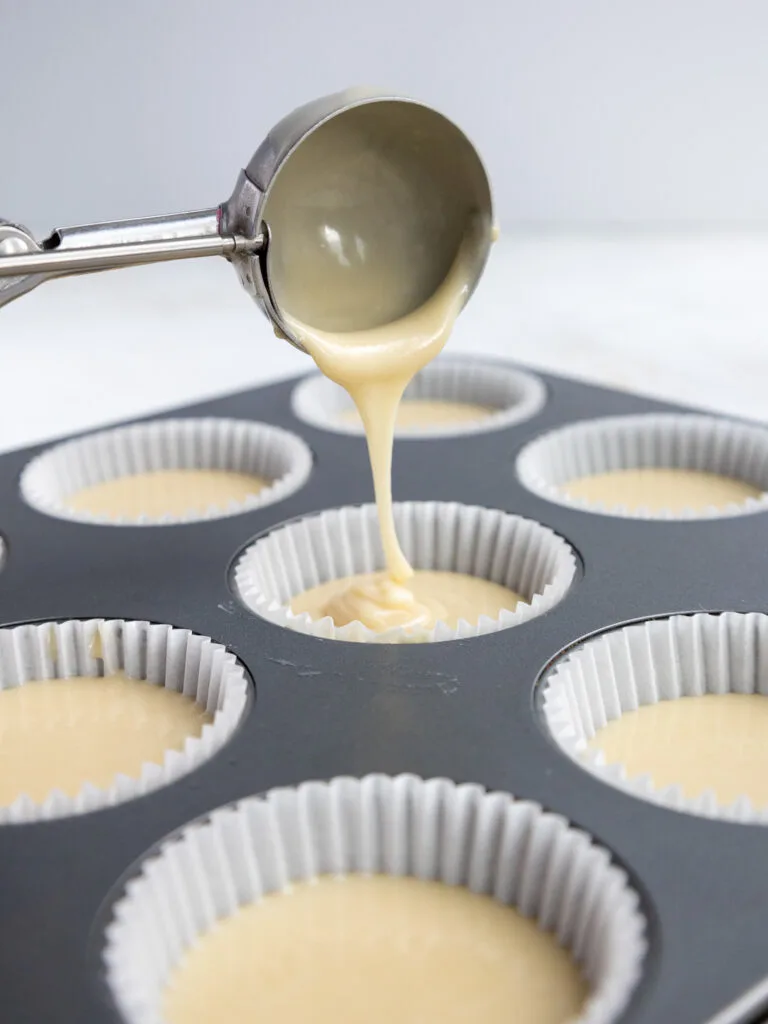 image of vanilla cupcake batter being scooped into cupcake liners