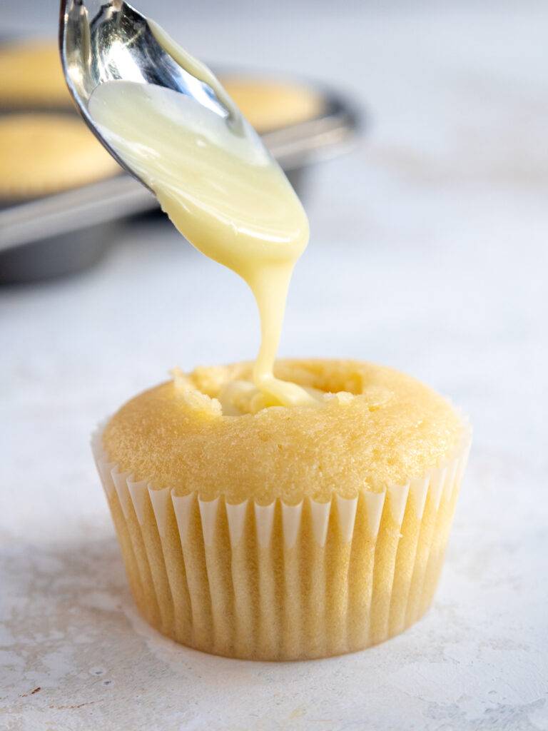 image of a vanilla cupcake being filled with white chocolate ganache