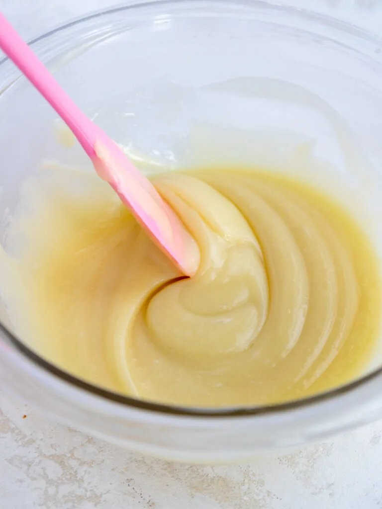 image of white chocolate ganache being mixed together with a pink spatula