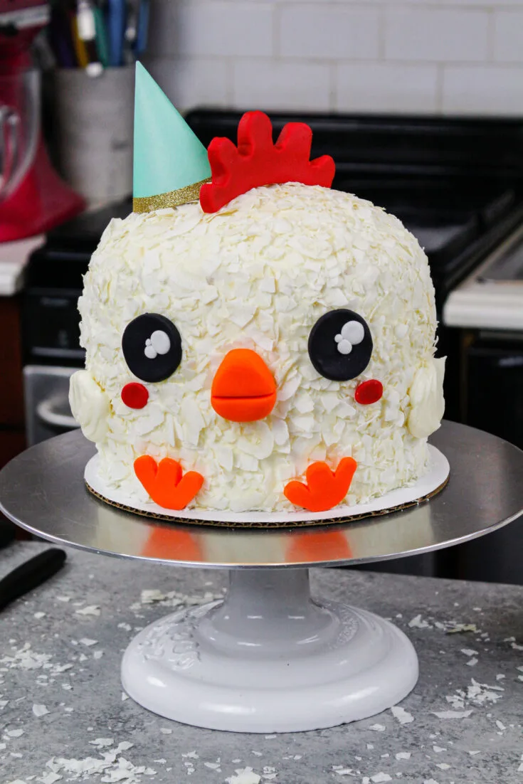 image of a chicken birthday cake made with fluffy coconut cake layers, coconut buttercream, and coconut feathers