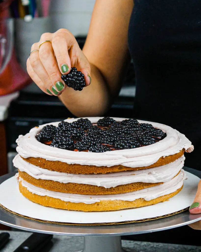 image of a blackberry layer cake being filled with fresh blackberries and blackberry jam