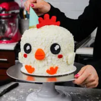 image of chelsey white placing a party hat on a spring chicken cake as part of her animal face series