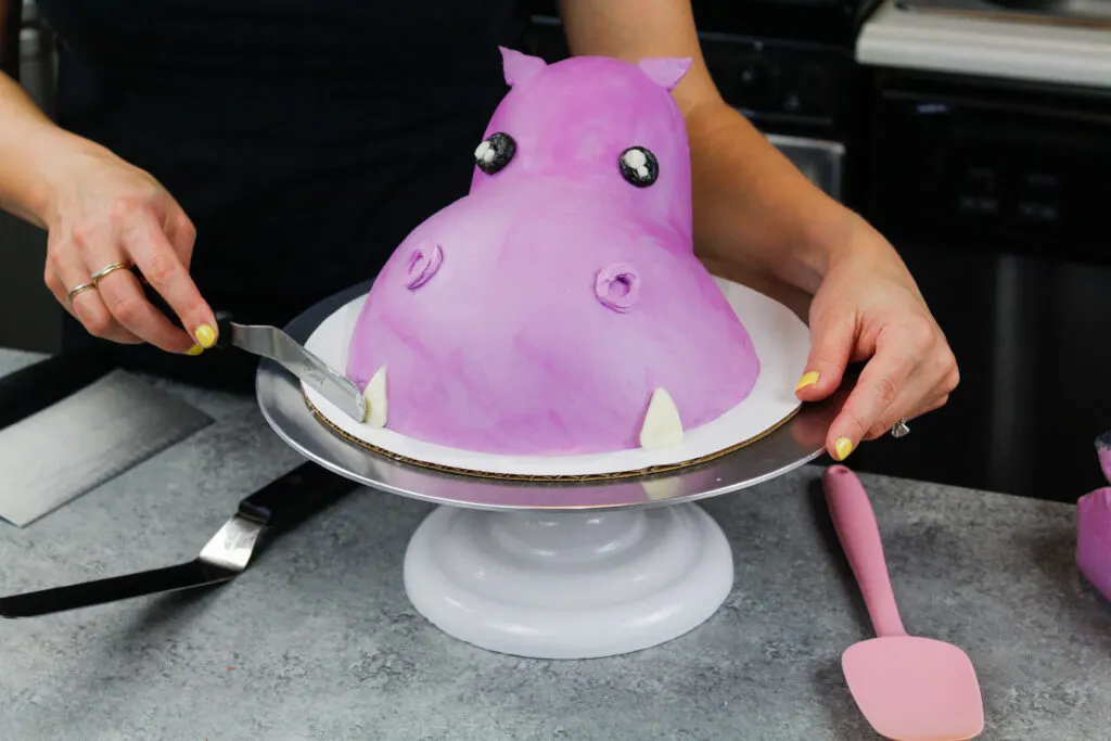 image of buttercream tusks being piped onto a hippo cake
