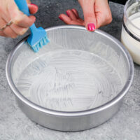 image of homemade cake release being brushed into a cake pan before batter is poured in to prevent the cake layers from sticking