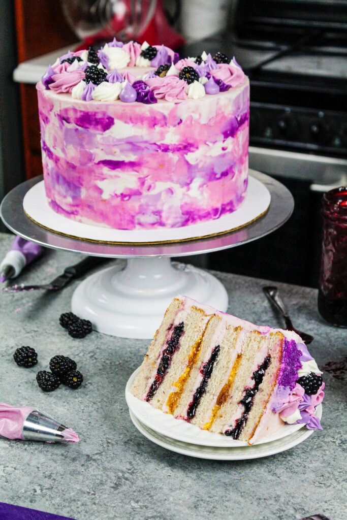 image of a beautiful blackberry and peach layer cake that's been cut into to show it's peach and blackberry filling