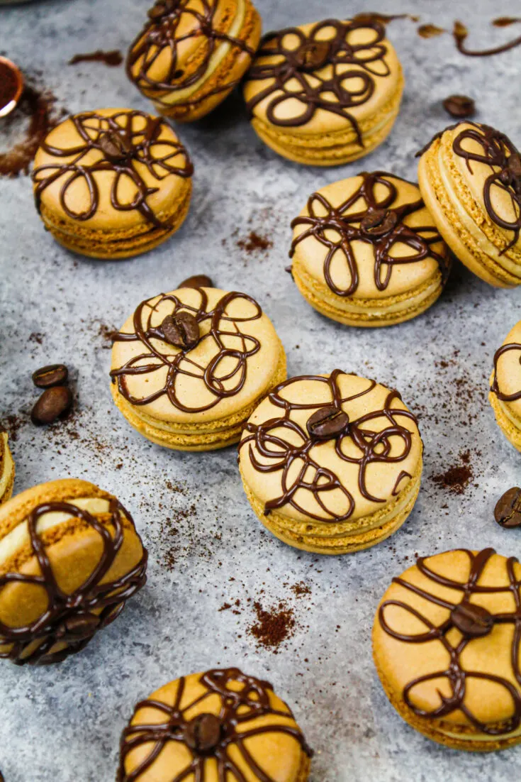 image of coffee macarons decorated with a drizzle of dark chocolate and a coffee bean