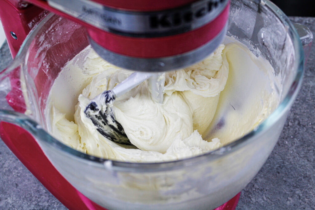 image of white vanilla buttercream being made in a kitchenaid mixer with a paddle attachment
