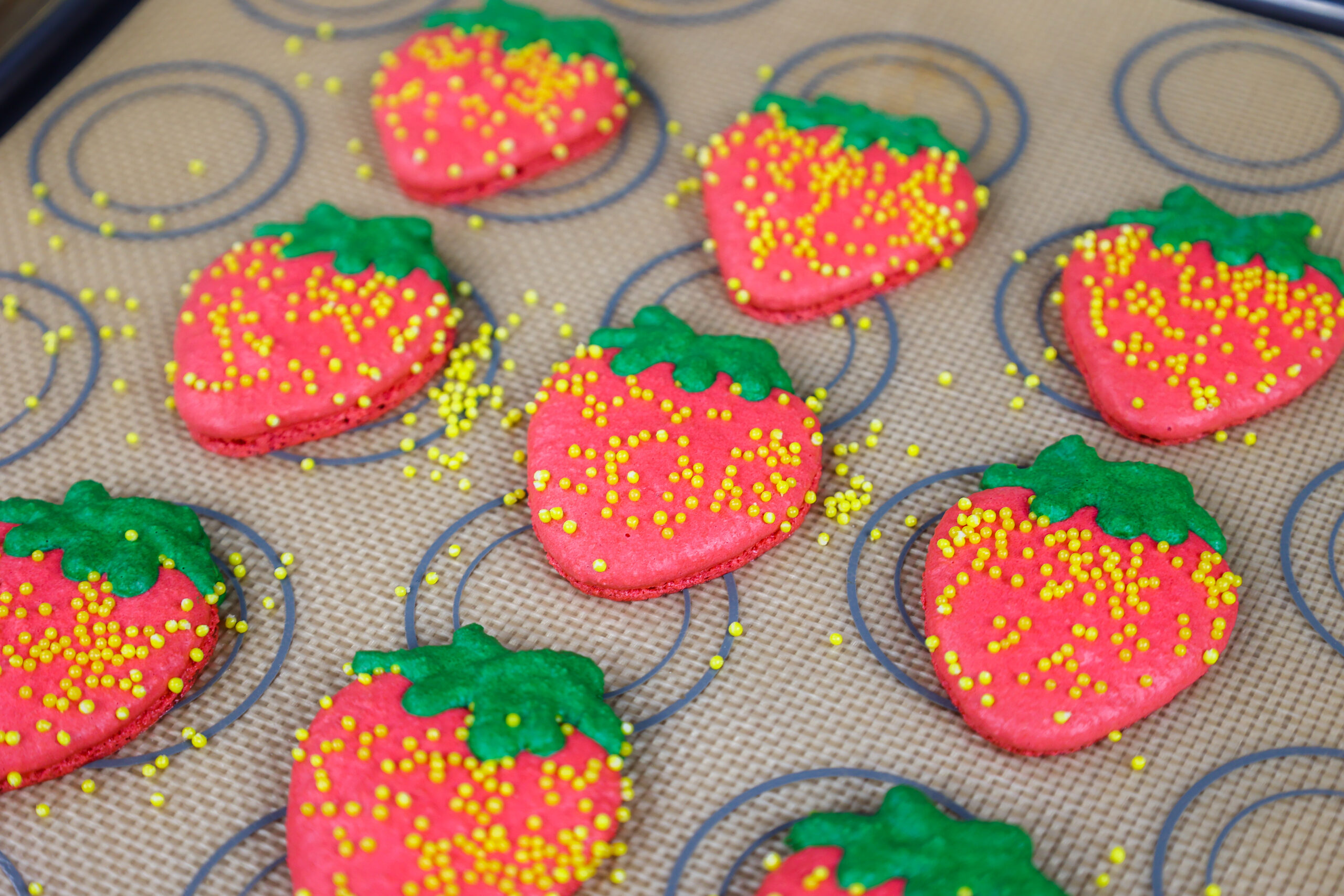 image of strawberry shaped macaron shells that have been baked and have nice feet