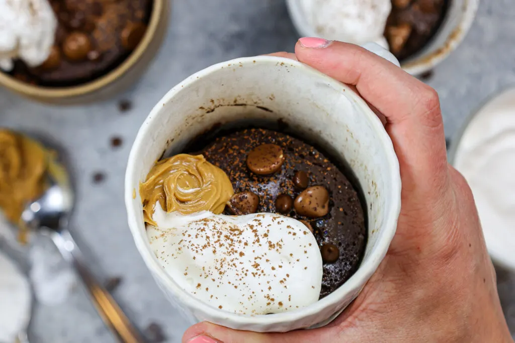 image of a protein mug cake topped with peanut butter and whipped cream