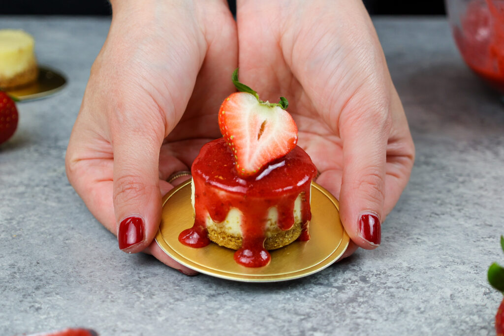 image of chelsey white of chelsweets holding a mini strawberry cheesecake in her hands
