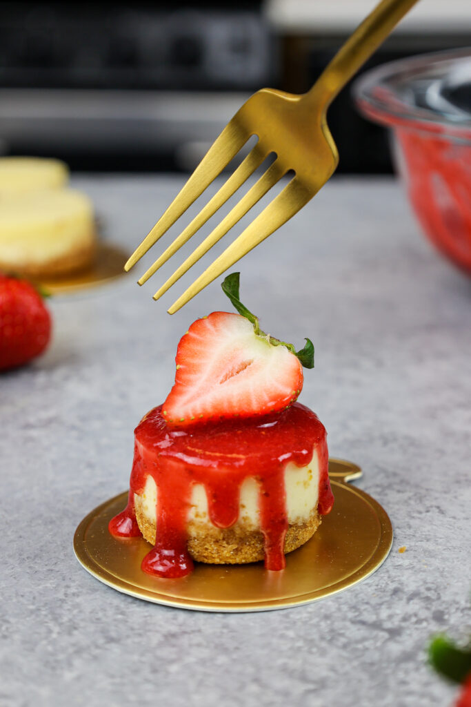 image of a mini strawberry cheesecake topped with a fresh strawberry garnish