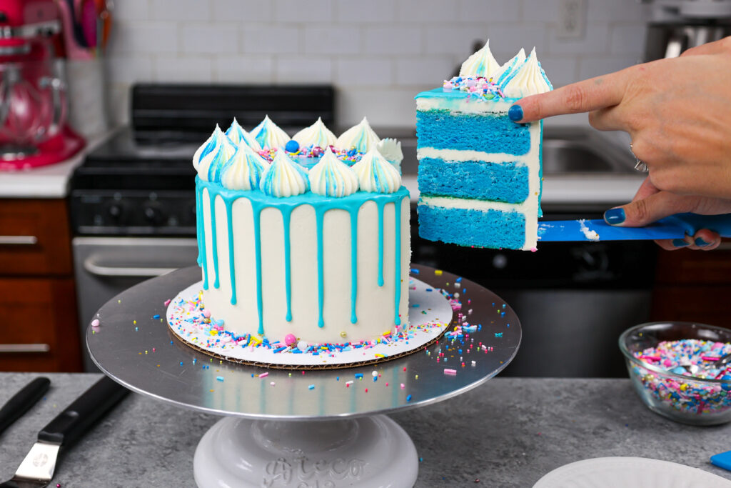 image of a blue drip cake being cut into to show its matching blue cake layers