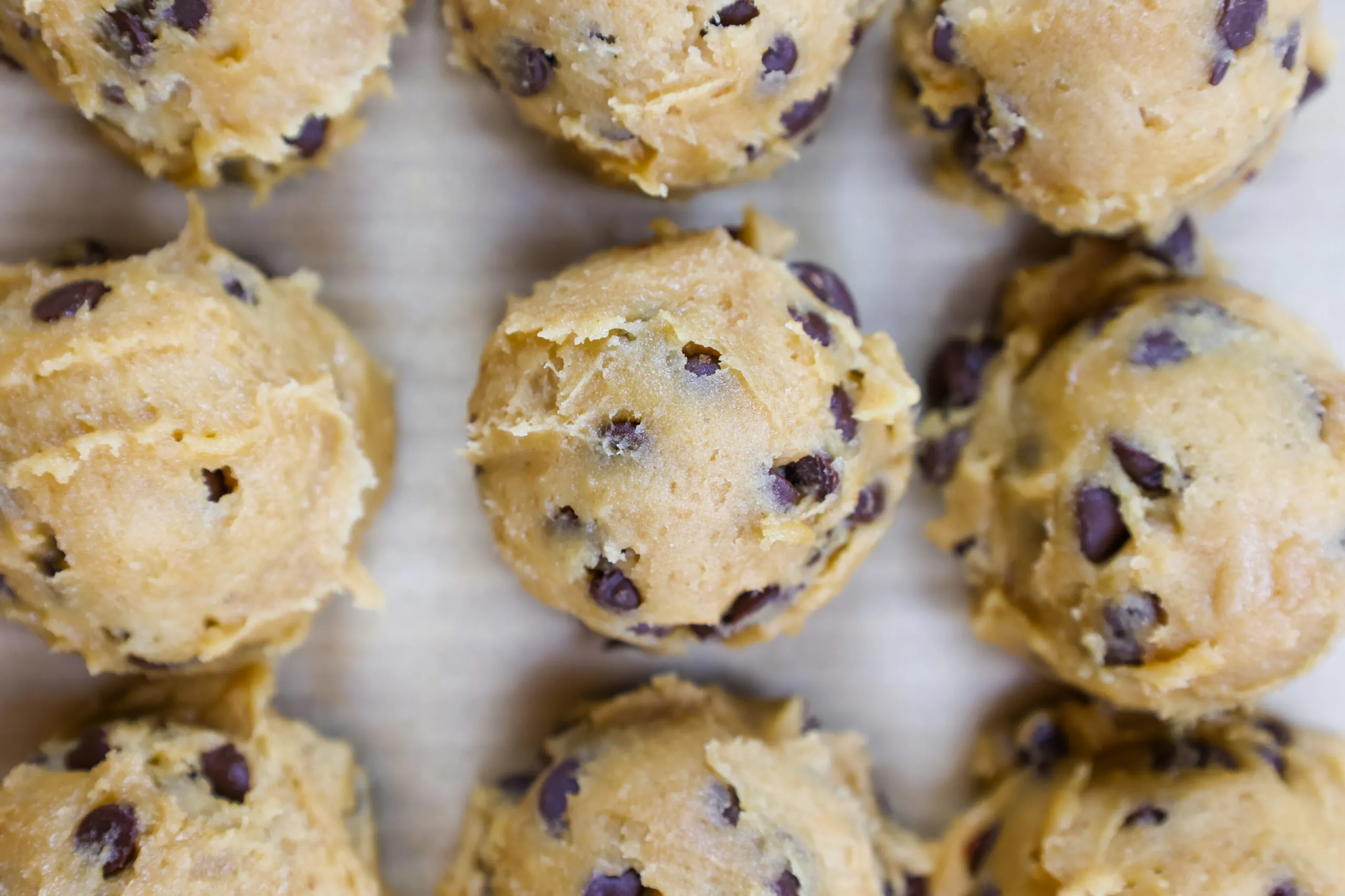 image of cream cheese chocolate chip cookie dough that's been scooped and is ready to be baked.