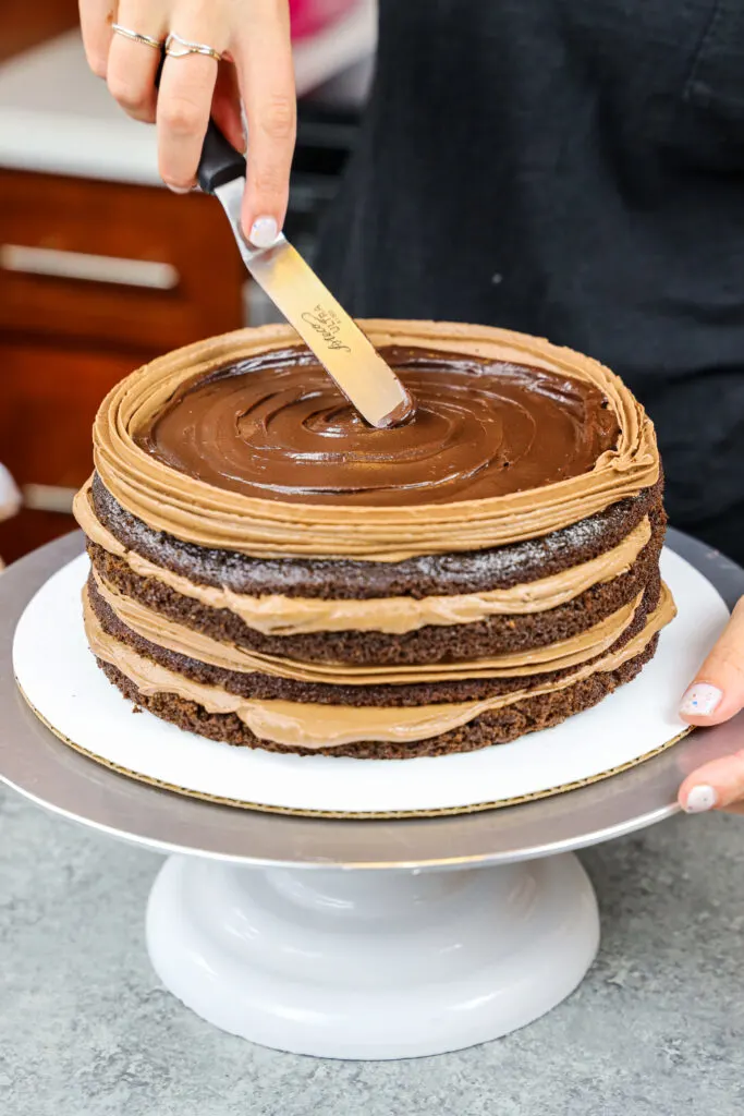 image of a triple chocolate cake being filled with milk chocolate buttercream and dark chocolate ganache