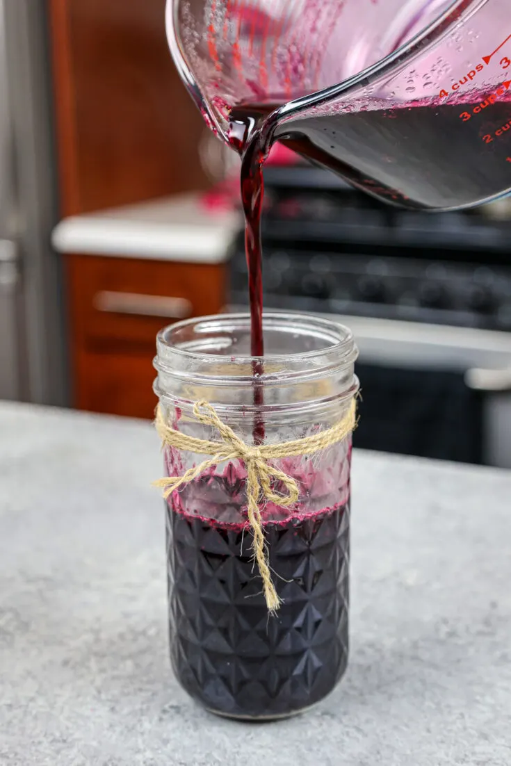 image of blueberry simply syrup being poured into a mason jar for storage