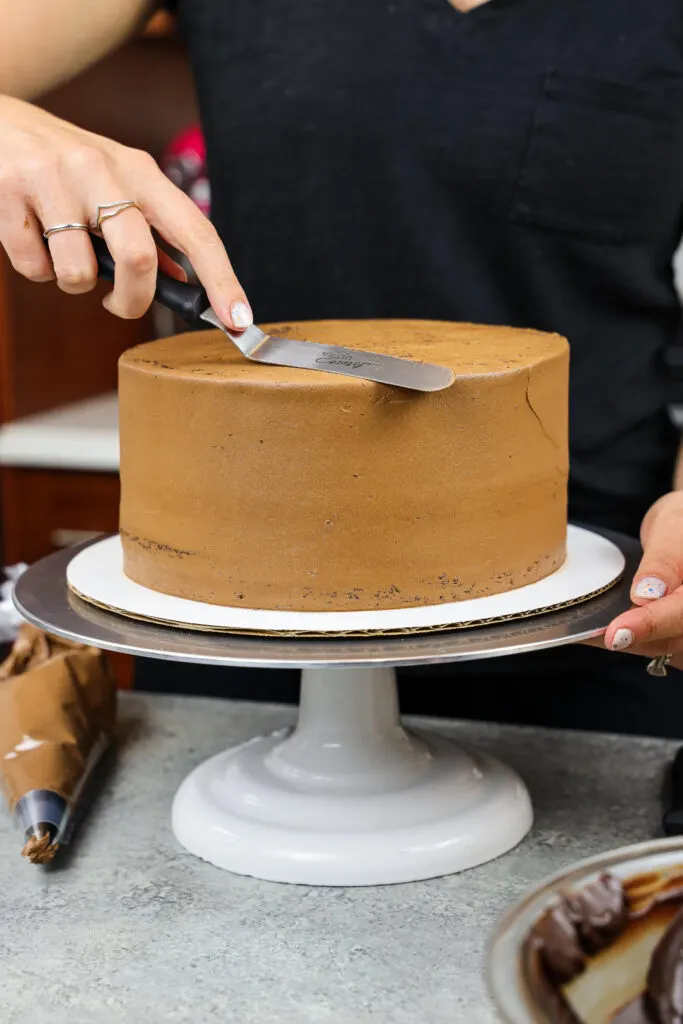 image of a triple chocolate cake being crumb coated before being decorated