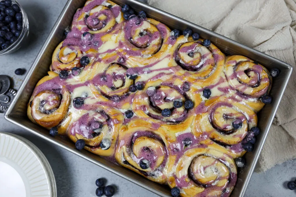 image of blueberry cinnamon rolls that have been baked and drizzled with vanilla and blueberry glaze