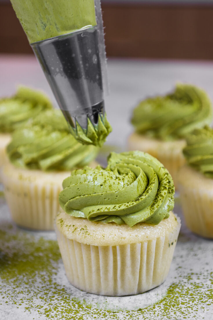 image of matcha buttercream being piped onto a vanilla cupcake