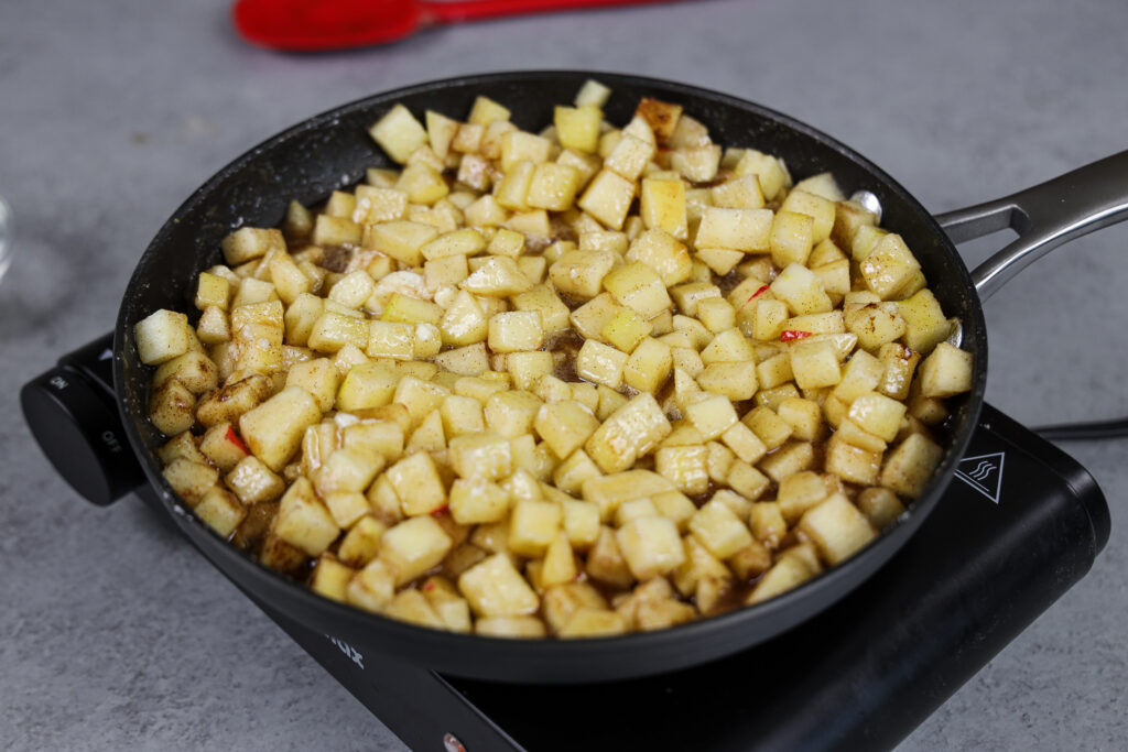 image of apple cake filling being cooked down in a large skillet with brown sugar, cinnamon and fresh lemon juice