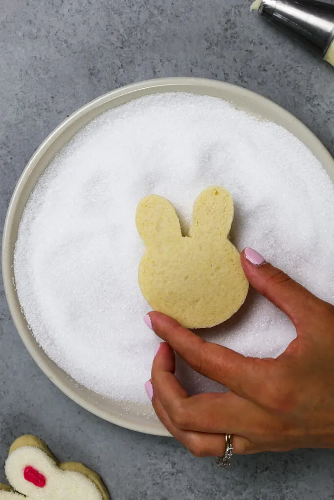 image of a rabbit cookie being dunked in sanding sugar to decorate it