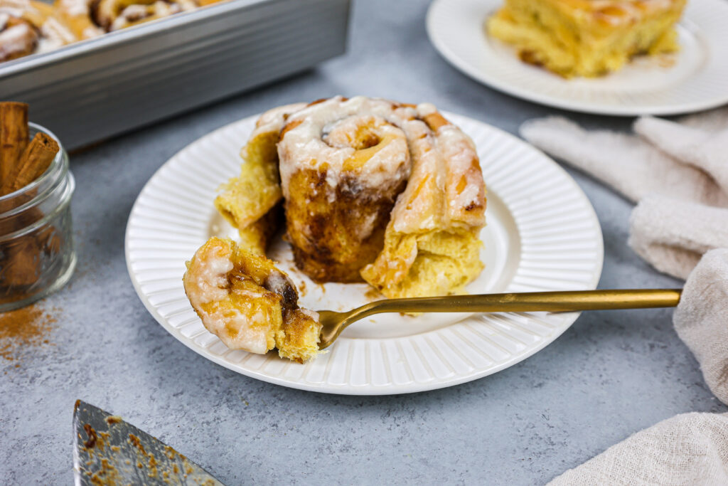 image of a pumpkin pie cinnamon roll that's been cut into to show how soft and tender it is and is being shared as part of a cinnamon roll round up
