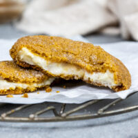 image of a pumpkin cheesecake cookie that's been broken open to show its cheesecake filling