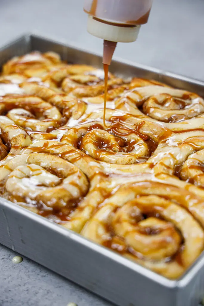 image of caramel being drizzled on top of caramel apple cinnamon rolls
