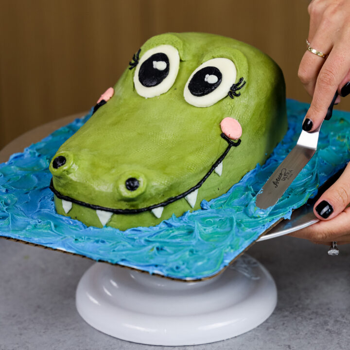 image of blue buttercream being added to cake board around a crocodile cake to make it look like it's in water