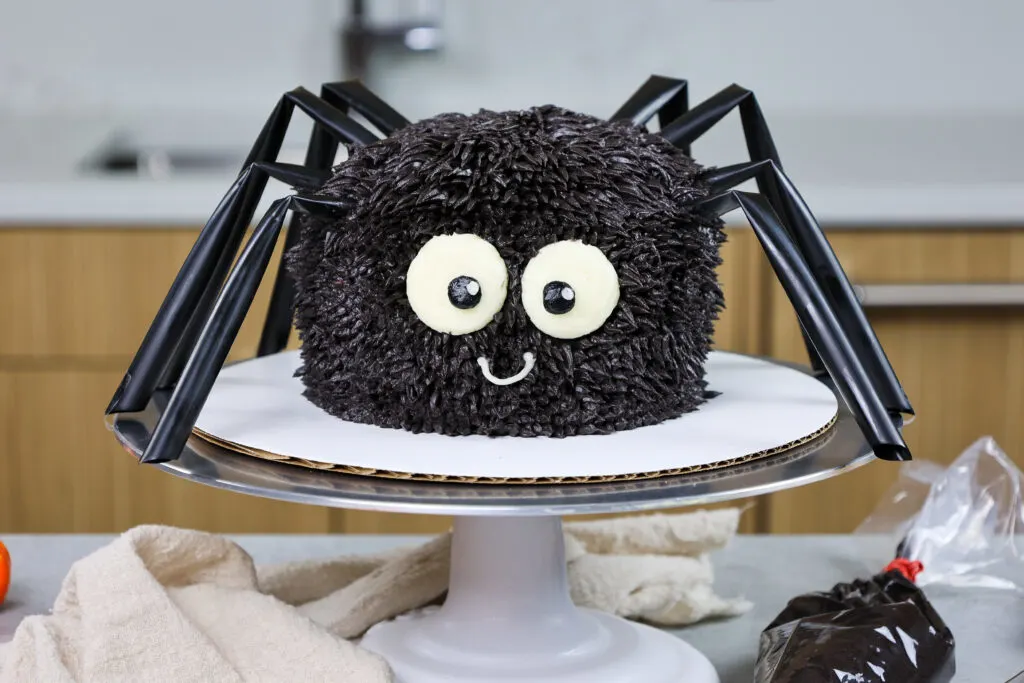 image of a cute and easy spider cake made with buttercream and straw legs