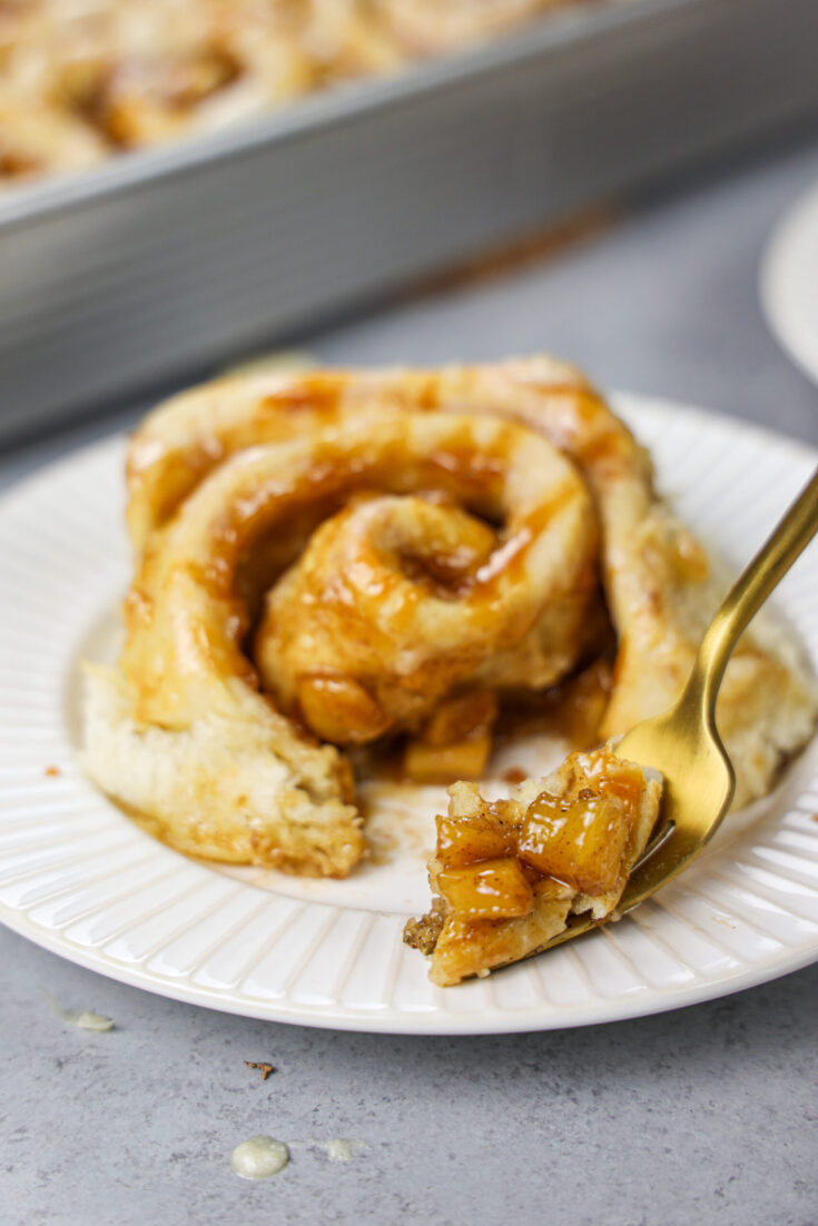 image of a caramel apple cinnamon roll that's been cut into the show it's delicious filling