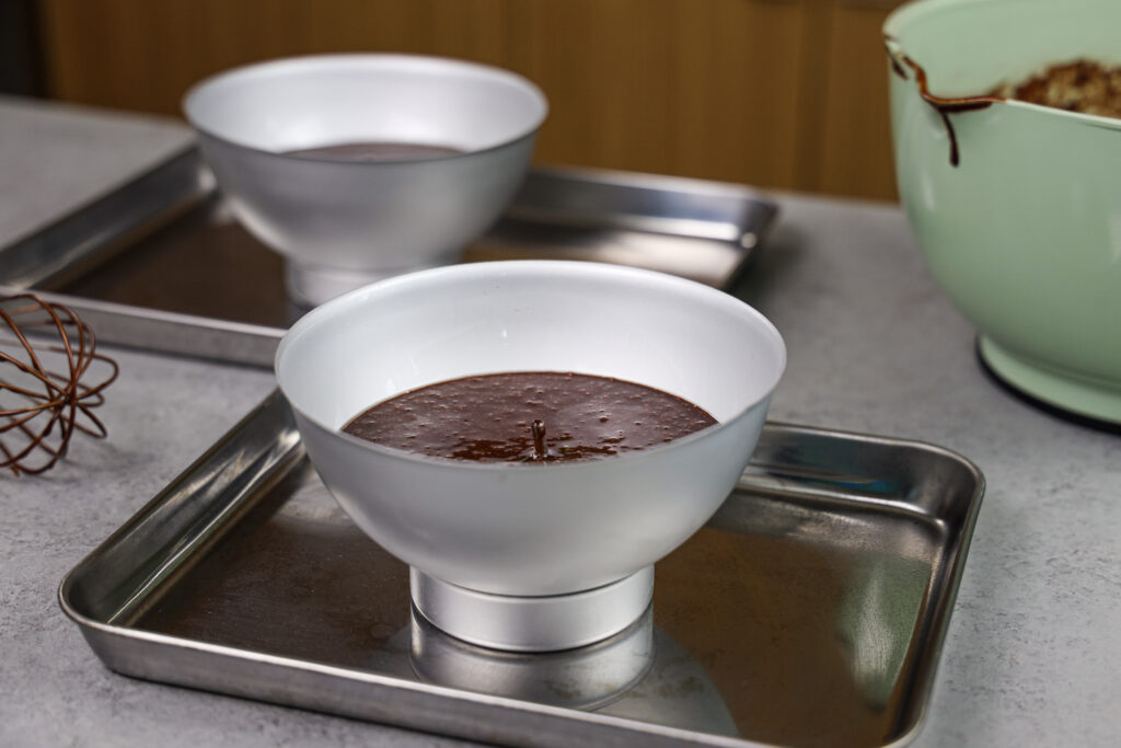 image of chocolate cake batter in domed cake pans ready to be baked