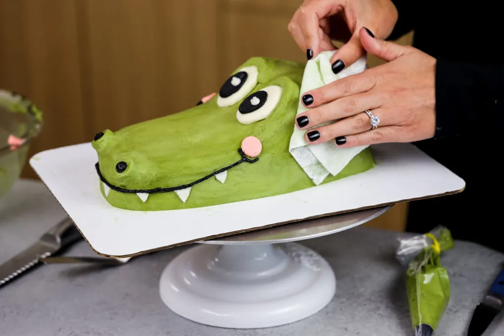 image of a crocodile cake being patted with a paper towel to add texture to make it look more like reptile skin