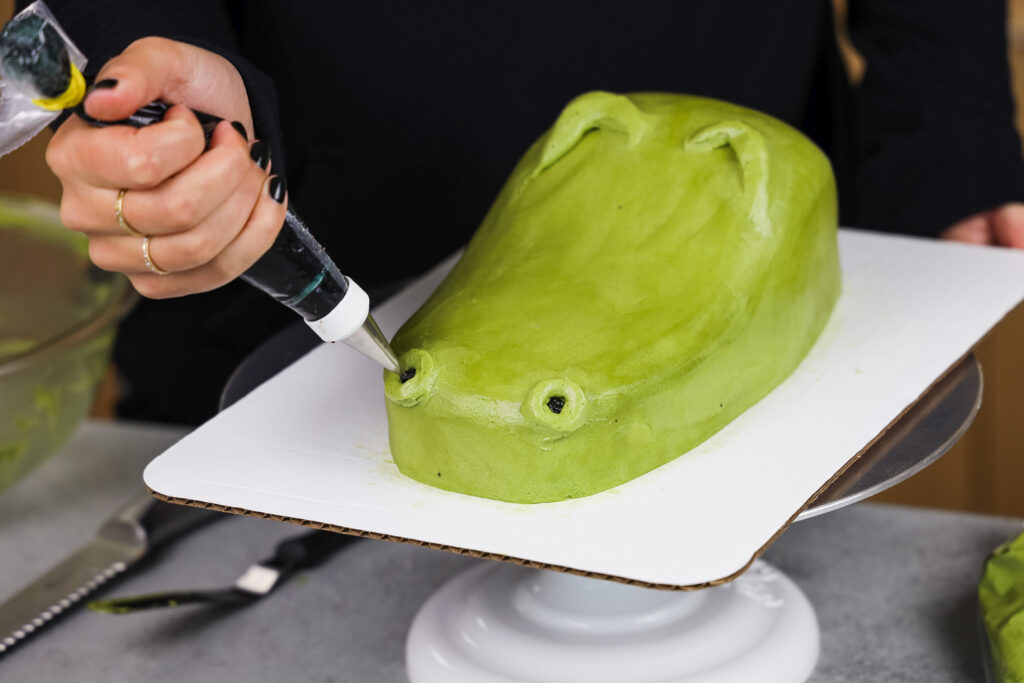 image of nostrils being piped with buttercream onto al crocodile cake