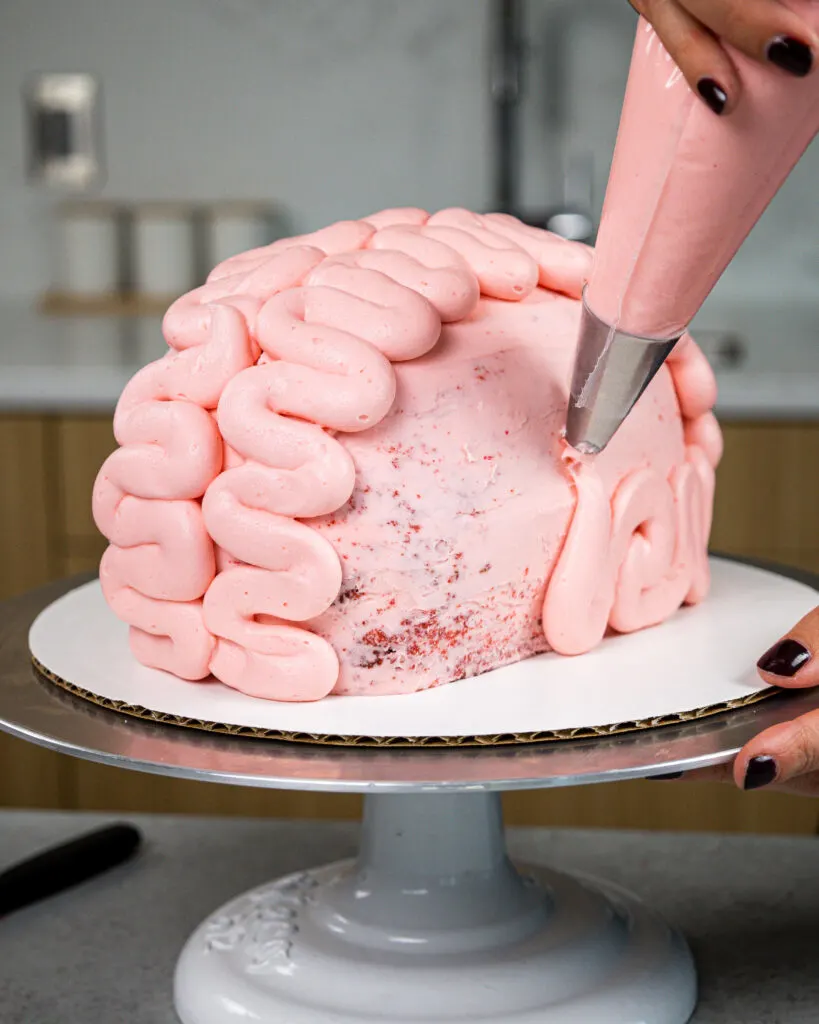 image of a brain cake that's being made with red velvet cake and pink cream cheese frosting