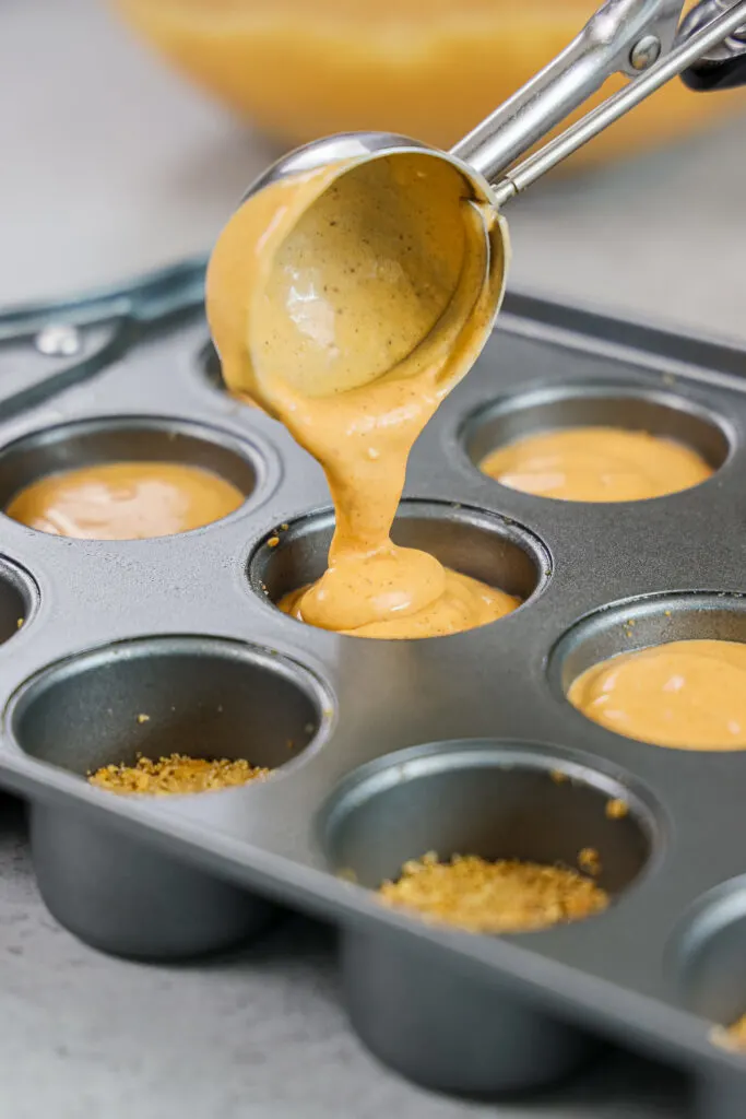 image of a mini cheesecake pan being filled with pumpkin cheesecake batter
