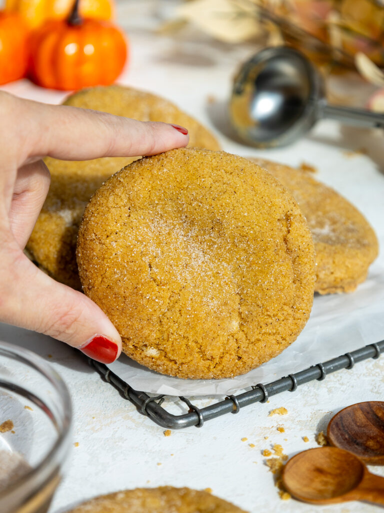 image of baked pumpkin cheesecake cookies stacked on a wire rack