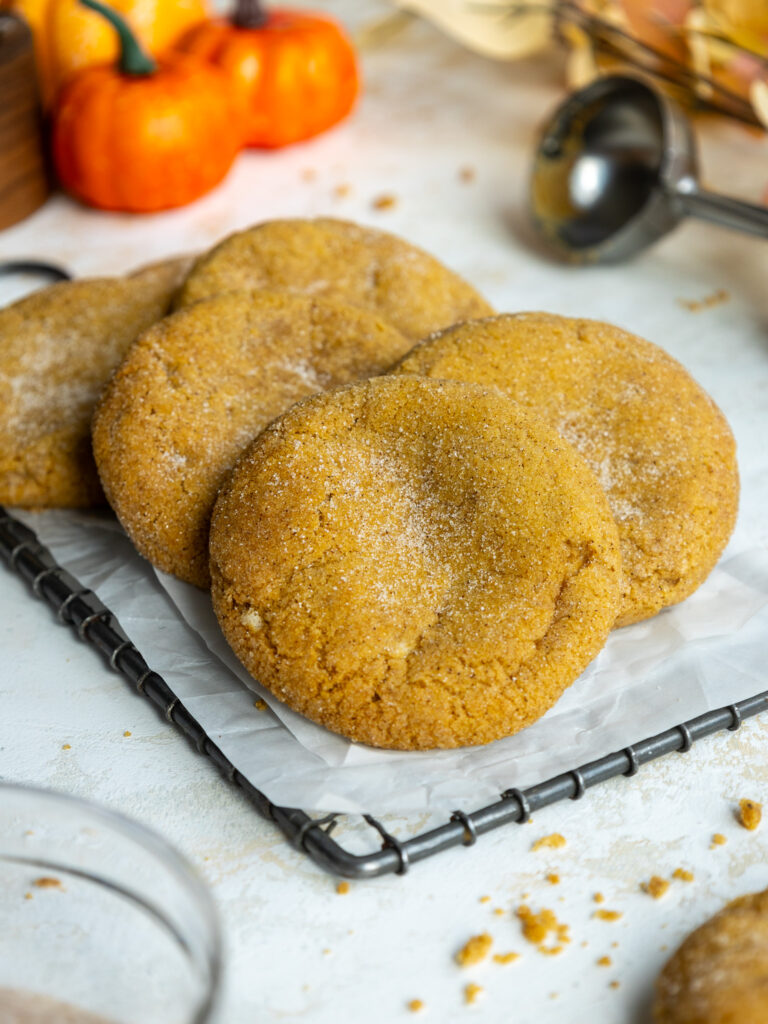 image of baked pumpkin cheesecake cookies stacked on a wire rack