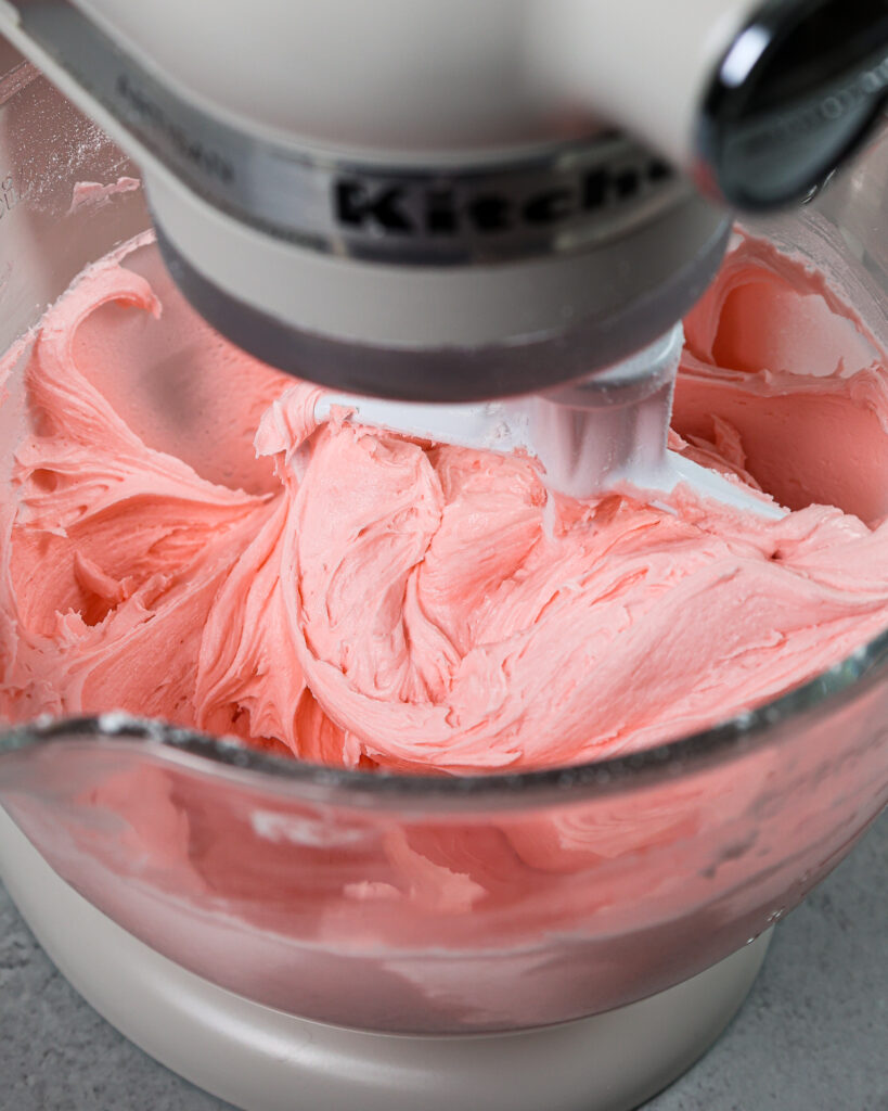 image of a bowl of pink cream cheese frosting being made in a kitchen aid mixer
