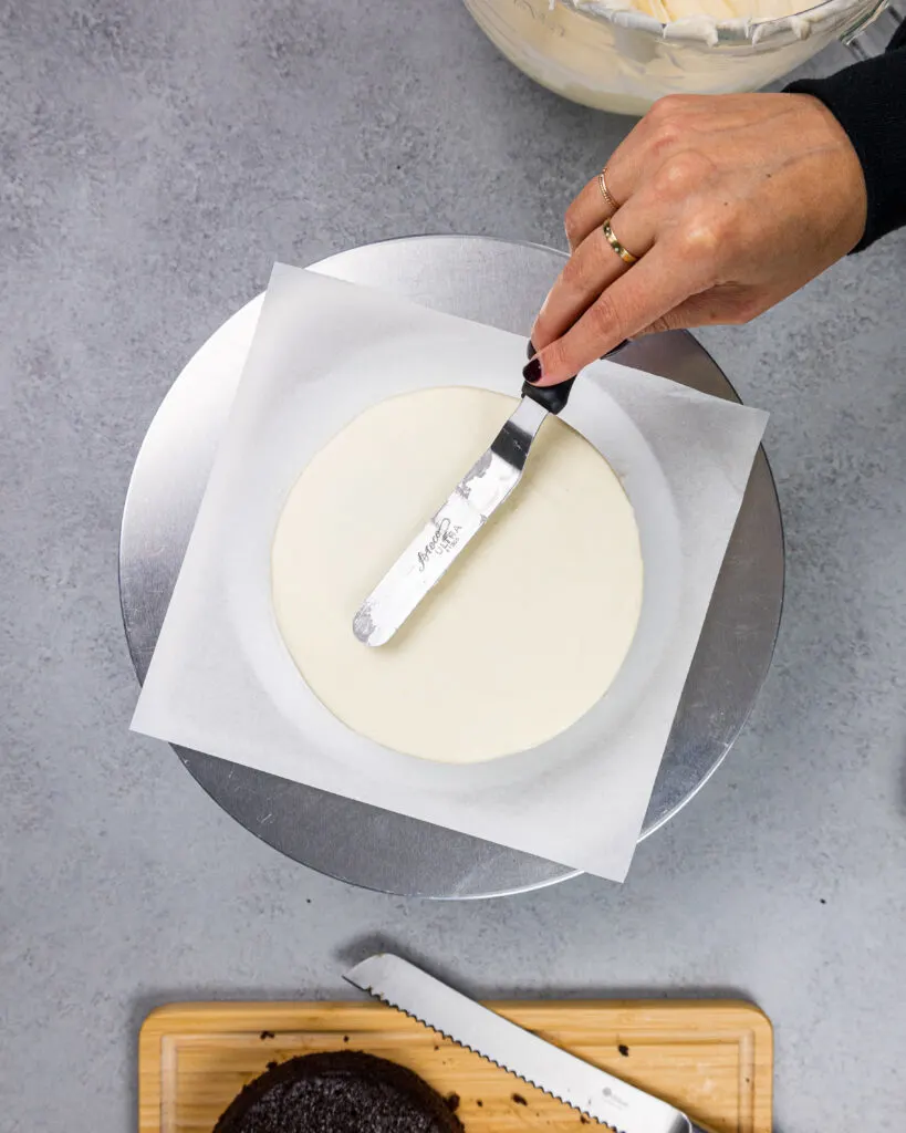 image of a small 6-inch cake being frosted and smoothed with a small offset spatula