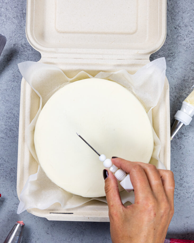 image of a message being sketched on top of a lunch box cake with a scribe before piping the message on the cake