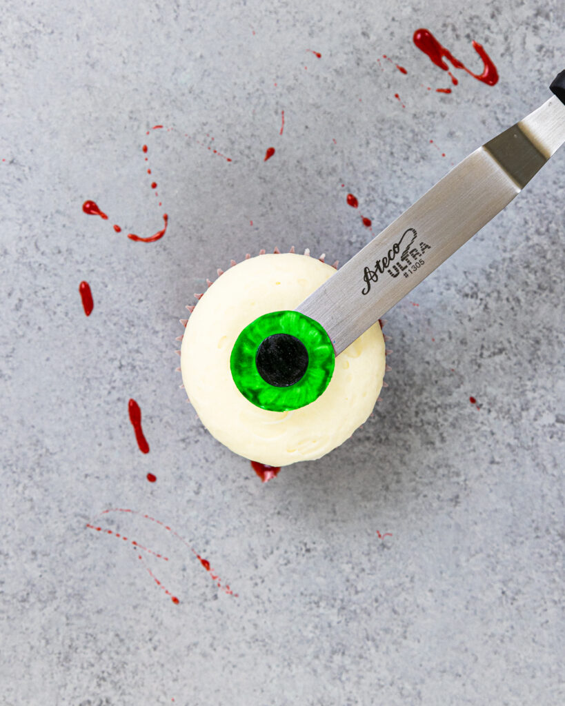 image of a fondant iris being placed on a cupcake to make an eyeball cupcake