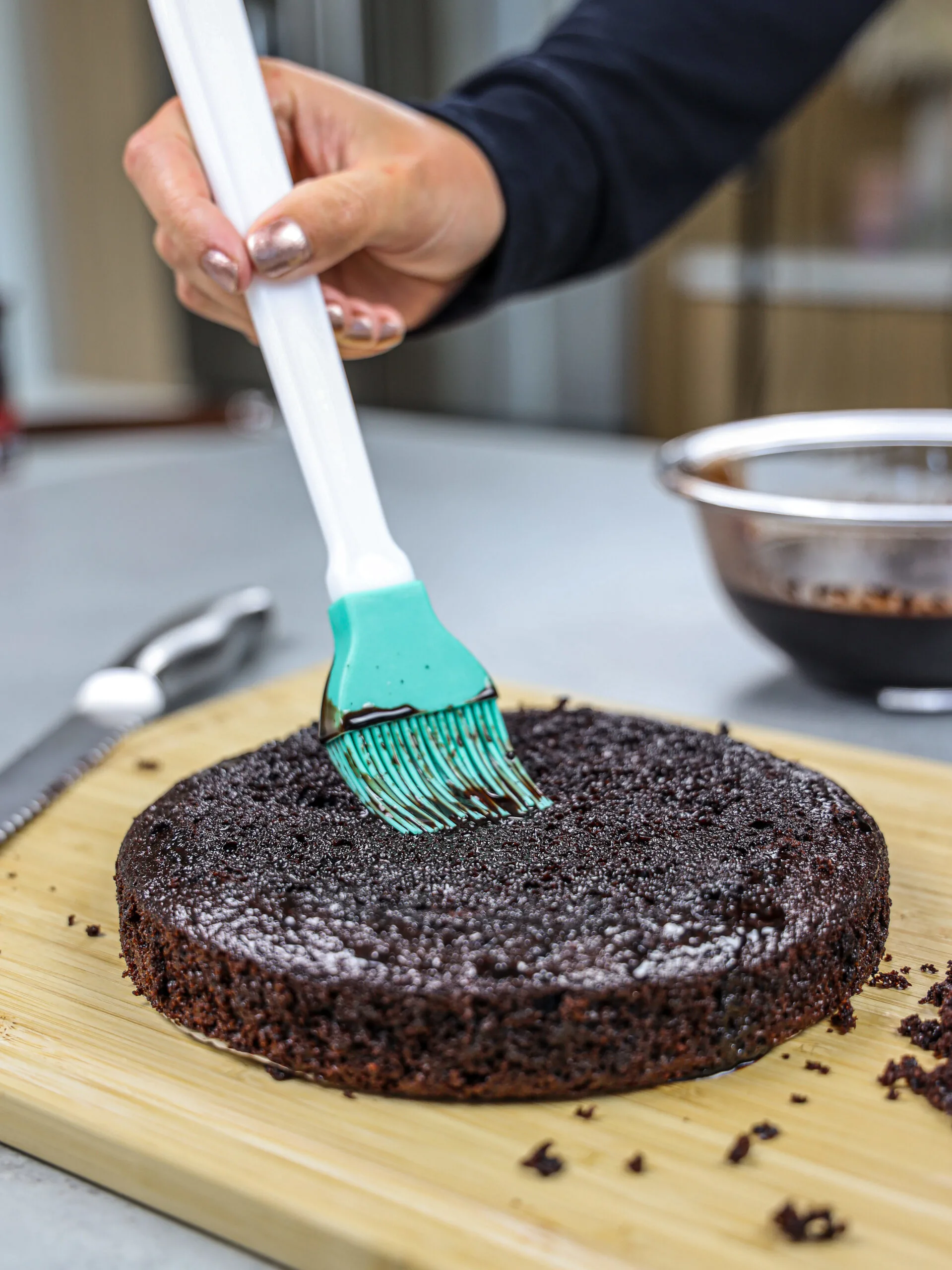 image of chocolate simple syrup being brushed onto a chocolate cake layer