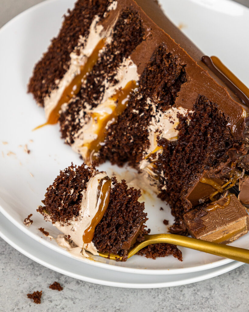 image of a slice of a milky way cake made with fluffy chocolate filling, homemade caramel filling, and moist chocolate cake layers