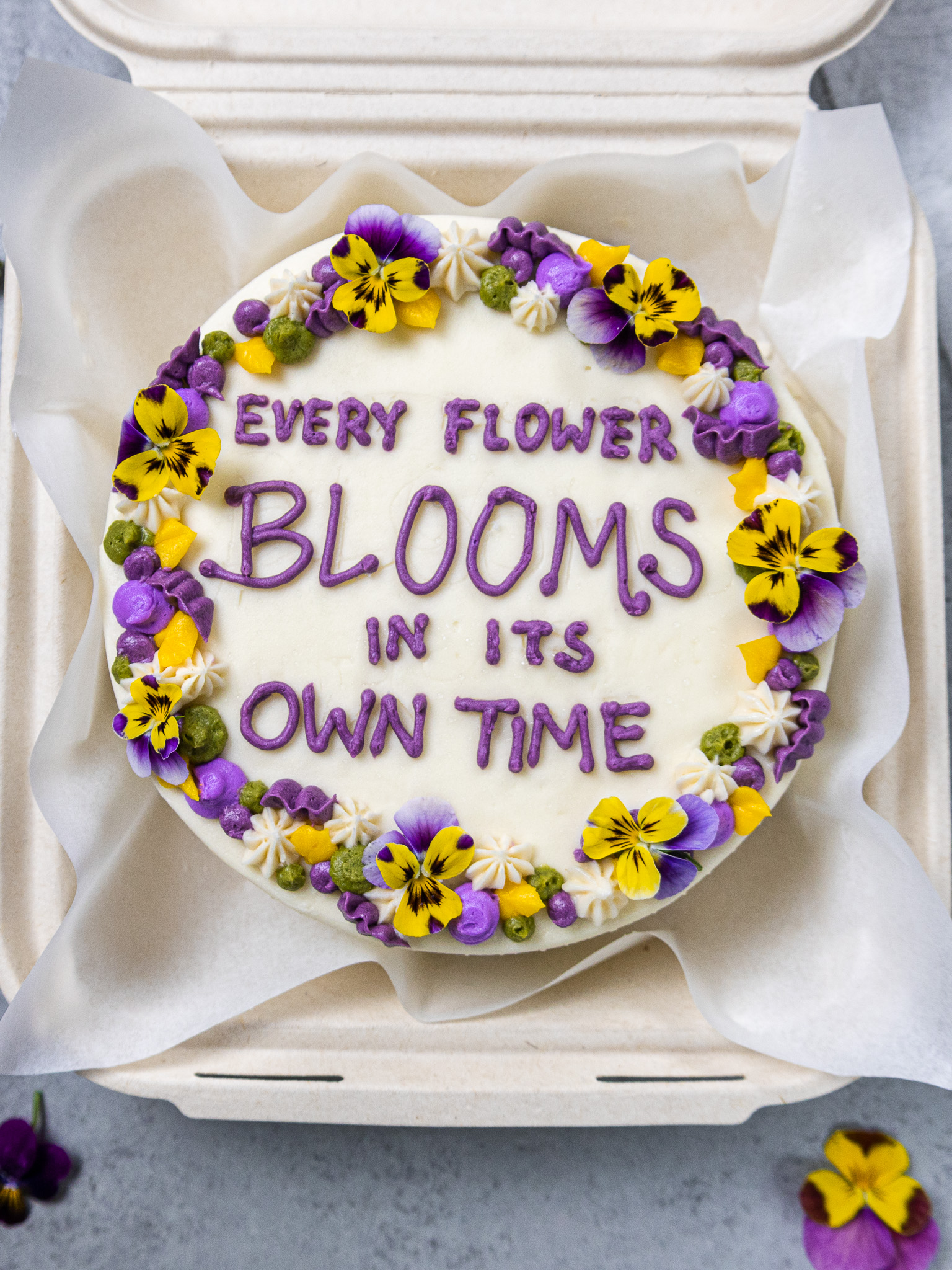 image of an adorable bento cake or lunch box cake decorated with a cute saying and edible flowers