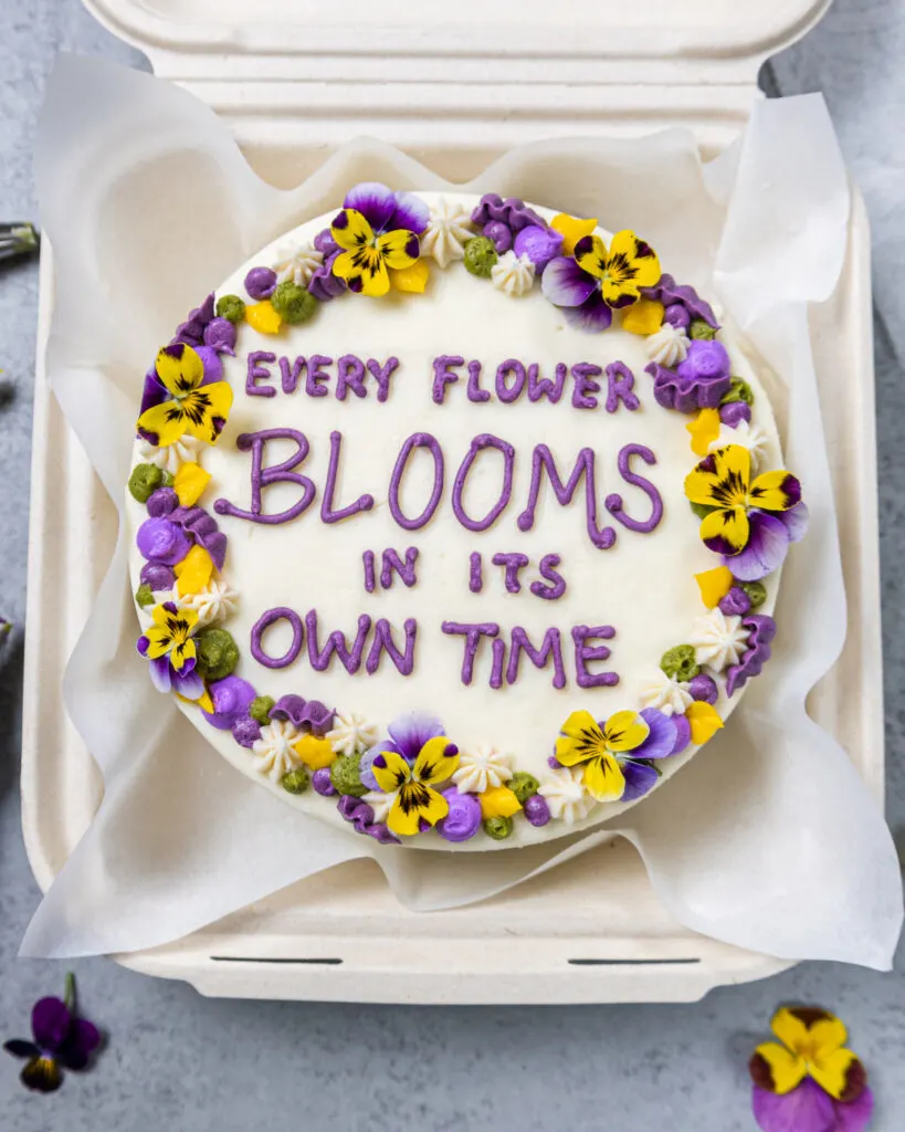 image of an adorable bento cake or lunch box cake decorated with a cute saying and edible flowers