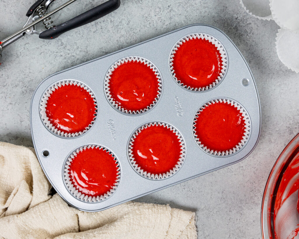 image of red velvet cupcake batter that's been scooped into a lined muffin tin and are ready to be baked